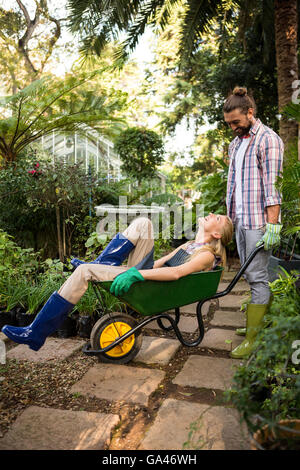 Glückliche Kollegen mit Schubkarre im Garten genießen Stockfoto