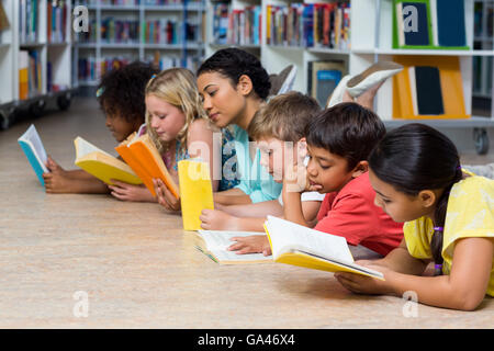 Lehrer mit Studenten, die Bücher zu lesen, beim hinlegen Stockfoto