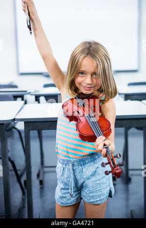 Glückliches Mädchen spielt Geige im Klassenzimmer Stockfoto