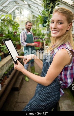 Porträt von glücklich Gärtner mit digital-Tablette am Gewächshaus Stockfoto