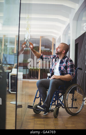 Handicap Geschäftsmann kleben Klebefuge Notizen auf Glasfenster Stockfoto