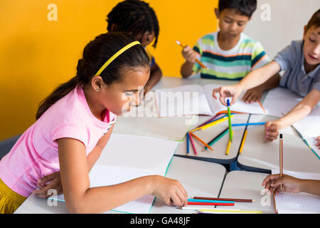 Kinder mit Büchern und Stiften auf Tisch Stockfoto