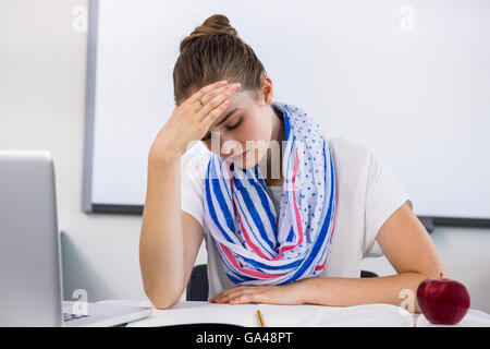 Betonte Lehrer leiden unter Kopfschmerzen im Klassenzimmer Stockfoto