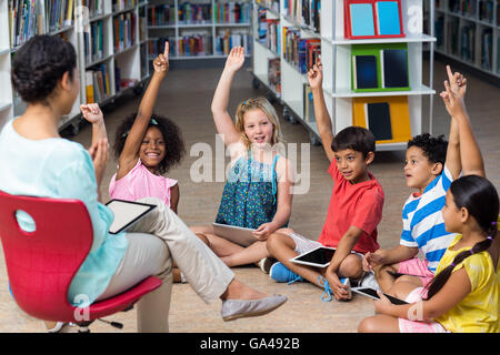 Lehrer auf Stuhl von Kindern Hände erhebend Stockfoto