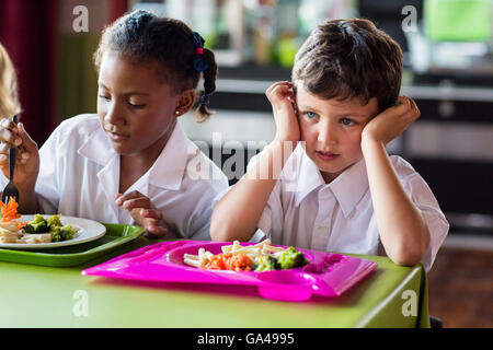 Nachdenkliche junge mit Klassenkameraden in der Kantine Stockfoto