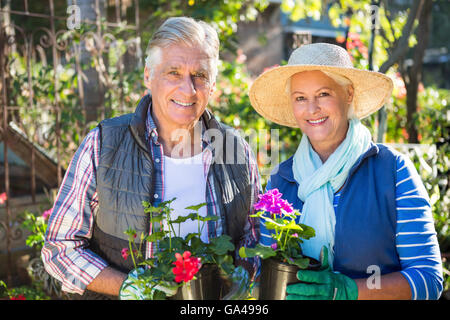 Porträt des glücklichen Paares hält Topfpflanzen im Garten Stockfoto