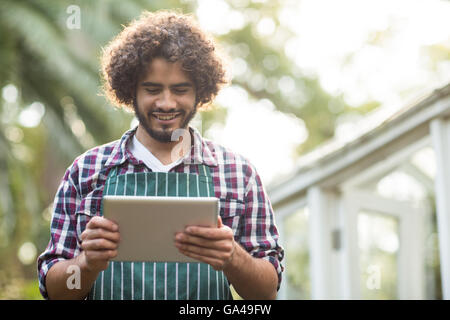 männliche Gärtner mit Tablet-PC am Gewächshaus Stockfoto