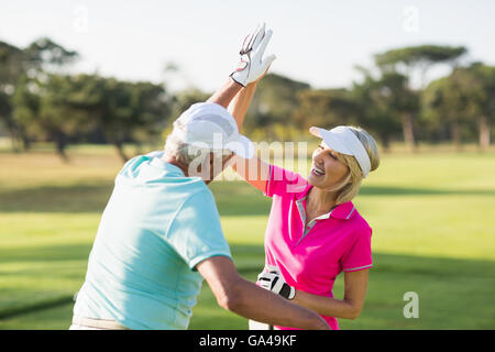 Fröhliche Golfspieler paar geben hohe fünf Stockfoto