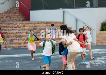 Glückliche Kinder laufen in Richtung Lehrer Stockfoto