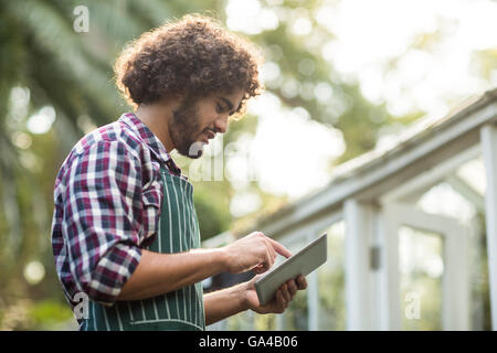 Männliche Gärtner mit Tablettcomputer außerhalb Gewächshaus Stockfoto