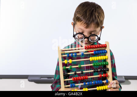 Süße junge spielt mit Abacus im Klassenzimmer Stockfoto