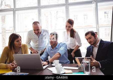 Geschäftsleute, die mit Technologien im Tagungsraum Stockfoto