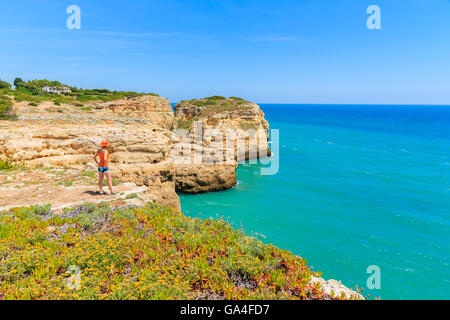 Junge Frau Touristen stehen auf Felsen und mit Blick auf den schönen Strand in der Nähe von Carvoeiro Stadt, Region Algarve, Portugal Stockfoto