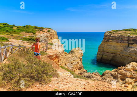 Junge Frau Tourist auf Klippe Felsen stehen und blickte auf dem Meer an der Küste von Portugal, Algarve-region Stockfoto