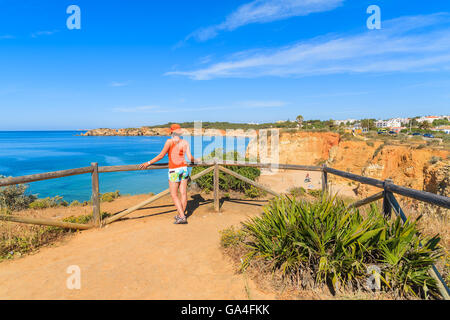 Junge Frau Touristen stehen auf Sicht und mit Blick auf den Strand Praia da Rocha, Portugal Stockfoto