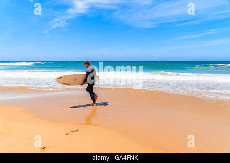 PRAIA DO AMADO BEACH, PORTUGAL - 15. Mai 2015: Surfer zu Fuß auf Praia tun Amado Strand mit Wellen schlagen Ufer, Region Algarve, Portugal. Stockfoto