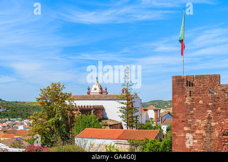 Blick auf den Schlossturm mit portugiesischer Flagge und die Kathedrale, die Gebäude der Stadt Silves, die Region Algarve, Portugal Stockfoto