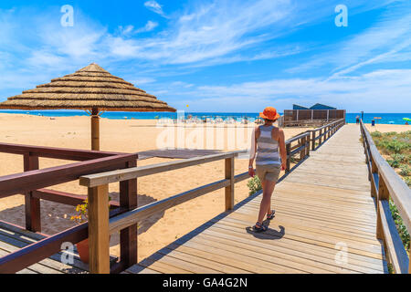 Junge Frau Tourist auf Holzsteg zu Fuß zum Sandstrand in Armacao de Pera Küstenstadt, die Region Algarve, Portugal Stockfoto