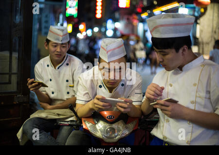 Chinesische Jugendliche spielen Sie mit ihren Smartphones und soziale Netzwerke in Peking, China Stockfoto