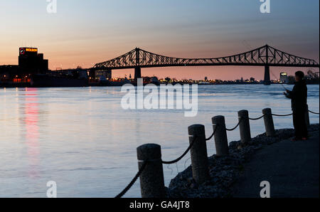 Ein Mann Angeln vom Parc De La Cite du Havre und Pont Jacques Cartier (Montreal Harbour Bridge) und der Molson Brauerei in der Abenddämmerung Stockfoto