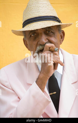 Gut gekleidete kubanischen Gentleman in rosa Blazer mit Krawatte sitzen im freien Rauchen einer Zigarre, Plaza Major, Trinidad, Kuba, Karibik Stockfoto