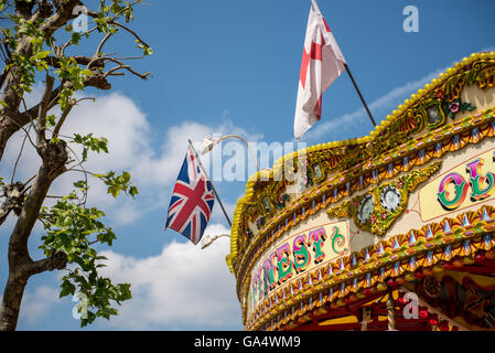 Festplatz Karussellfahrt mit Union Jack und St George Kreuz Fahnen von der Felge Stockfoto