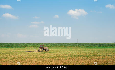 modernen roten Traktor im landwirtschaftlichen Bereich; Mechanismus. Traktor Pflügen Land. Harvester Weizen säen. Stockfoto