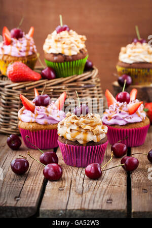 Verschiedene leckere Muffins verziert mit Karamell und frischen Beeren Stockfoto