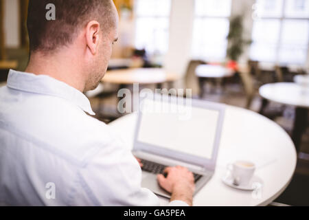 Rückansicht des Geschäftsmann Tippen auf Laptop im Kreativbüro Stockfoto