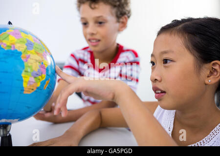 Jungen und Mädchen betrachten Glob im Klassenzimmer Stockfoto