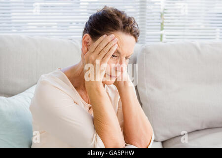Frau mit Kopf in Händen sitzend auf sofa Stockfoto