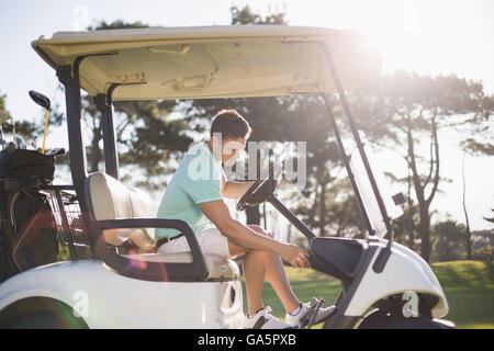 Seitenansicht der Golfer Mann sitzt im Golfbuggy Stockfoto