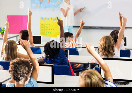 Lehrerin zeigt Schüler mit erhobenen Händen im Klassenzimmer Stockfoto