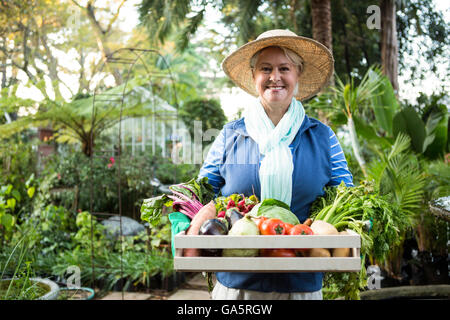 Porträt von glücklich zuversichtlich Gärtner mit Gemüse-Kiste im Garten Stockfoto