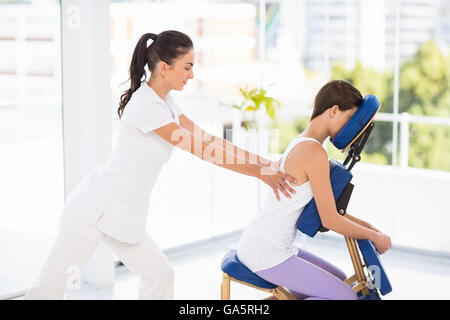 Frau auf Stuhl von Masseurin massiert Stockfoto