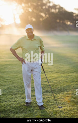 Lächelnde Golfer mit Hand auf Hüfte haltend Golf club Stockfoto