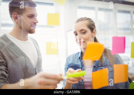 Geschäftsfrau mit Kollegen kleben Klebefuge Notizen im Büro Stockfoto