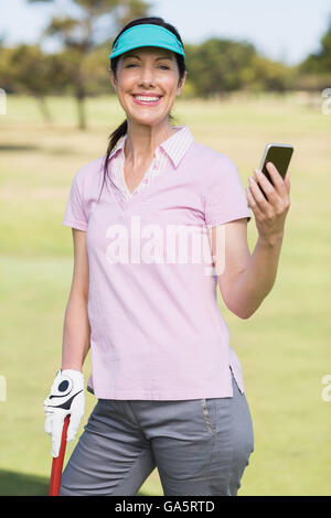 Porträt des Lächelns Golfer Frau mit Telefon Stockfoto