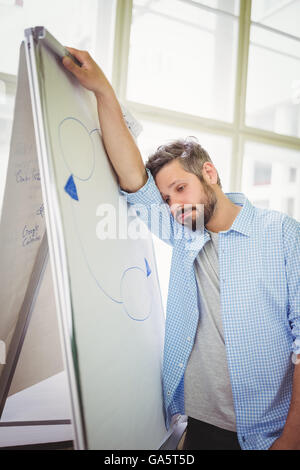 Müde Geschäftsmann stützte sich auf Whiteboard im Büro Stockfoto