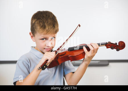 Porträt von lächelnden Schuljunge Geigenspiel im Klassenzimmer Stockfoto