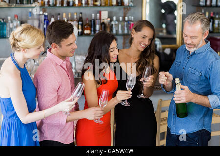 Freunde, die Suche nach Menschen, die Sektflasche zu öffnen Stockfoto