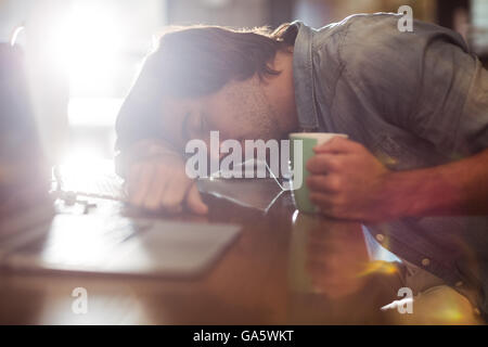 Mann schläft auf Tisch im Büro Stockfoto