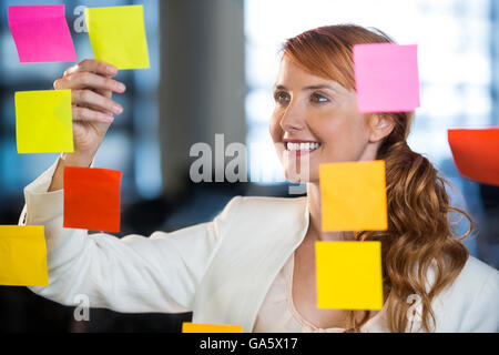 Geschäftsfrau, die durch Glas mit Klebstoff Noten gesehen Stockfoto