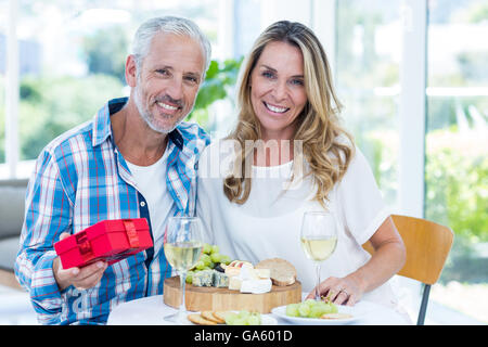 Reifer Mann halten Geschenk beim sitzen neben Frau Stockfoto
