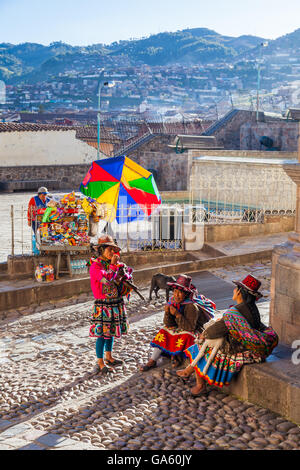 Drei peruanische Frauen und Tiere am Ende des Tages verbrachte posiert mit Touristen in Cusco Stockfoto