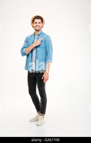 Fröhlich attraktiver junger Mann im karierten Hemd stehen und entfernt über weißem Hintergrund zeigend Stockfoto