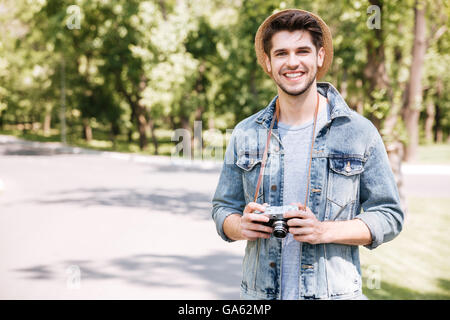 Glücklich schönen jungen Mann mit Hut mit alten Vintage Foto-Kamera im freien Stockfoto