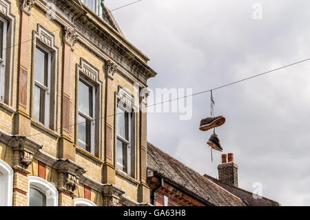 Turnschuhe hängen Powerlines gegen das Gebäude der Stadt von Winchester, UK Stockfoto