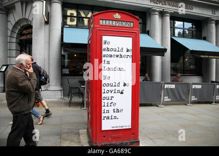 Ein Mann liest ein Angebot über eine rote Telefonzelle am Haymarket in der Londoner Innenstadt. Stockfoto