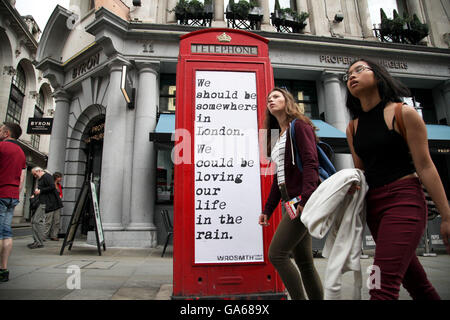 Frauen passieren ein Angebot auf eine rote Telefonzelle am Haymarket in der Londoner Innenstadt. Stockfoto